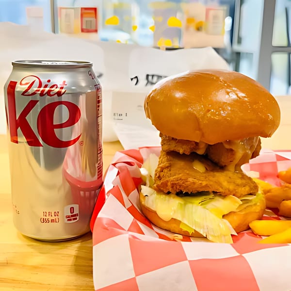 A Noori Chicken sandwich with fries and a Diet Coke on a red and white checkered paper.