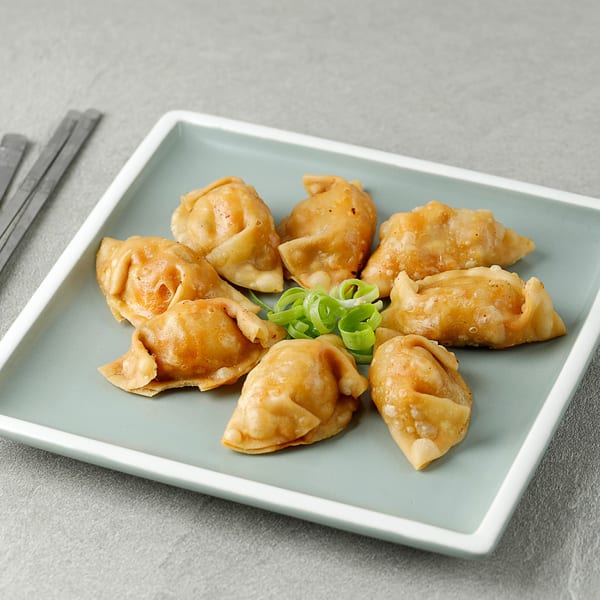 Golden-brown Korean dumplings, garnished with green onions, arranged on a light blue rectangular plate.